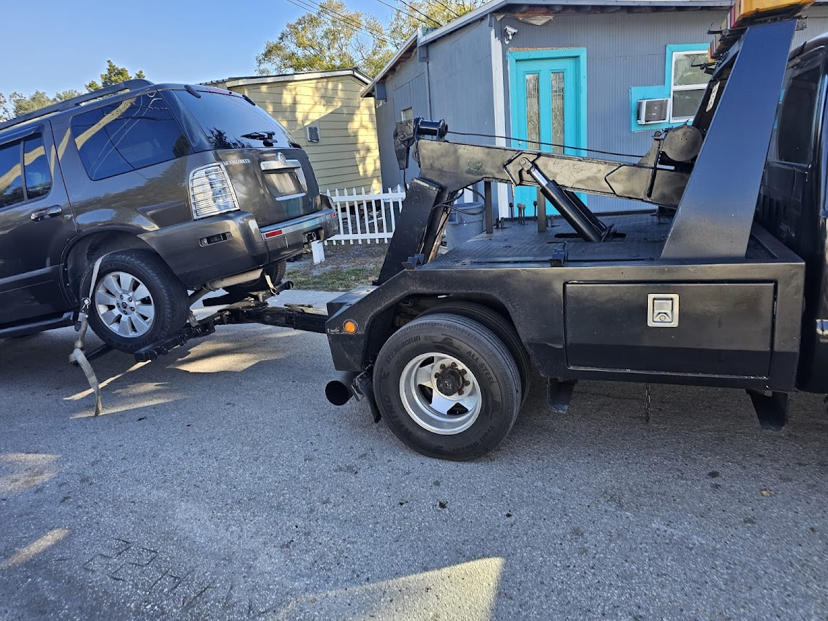 Black wrecker truck lifting an SUV