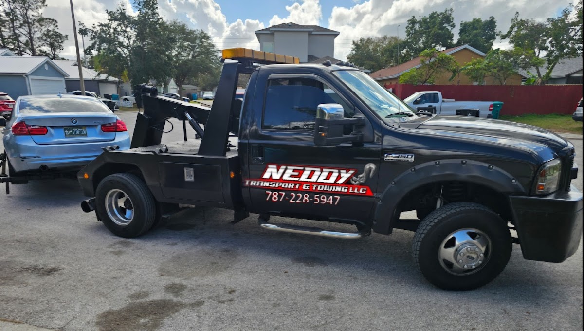Neddy Transport black wrecker truck with branding towing a BMW